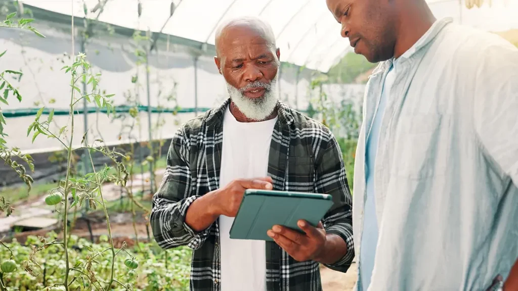 Smarter Farming- Greenlife Crop Protection Africa Agronomist advising farmer using tablet inside a greenhouse — representing Greenlife Crop Protection Africa’s modern approach to crop protection, nutrition, and agronomic support.